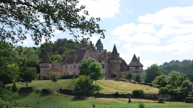 A castle with multiple towers and a large courtyard surrounded by lush greenery.