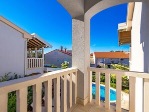 A balcony with a view of a swimming pool and neighboring houses.