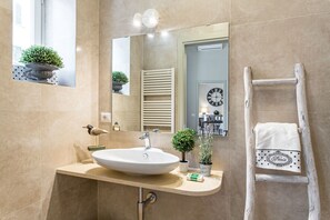 Ein Badezimmer mit großem Spiegel, Waschbecken, Handtuchhalter und einer Holzleiter.