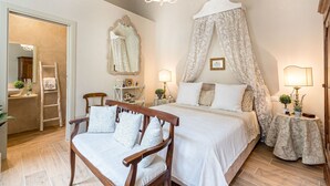A bedroom with a canopy bed, a wooden chair, a bedside table, a mirror, and a door leading to a bathroom. - Modern comfort in Lucca's Picturesque Canal District (Lucca)