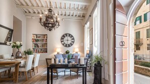 A cozy living room with a wooden ceiling, a large wall clock, a chandelier, and a bookshelf. - Modern comfort in Lucca's Picturesque Canal District (Lucca)