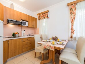 Una cocina compacta con armarios de madera, un microondas y una zona de comedor con una mesa dispuesta para dos personas.