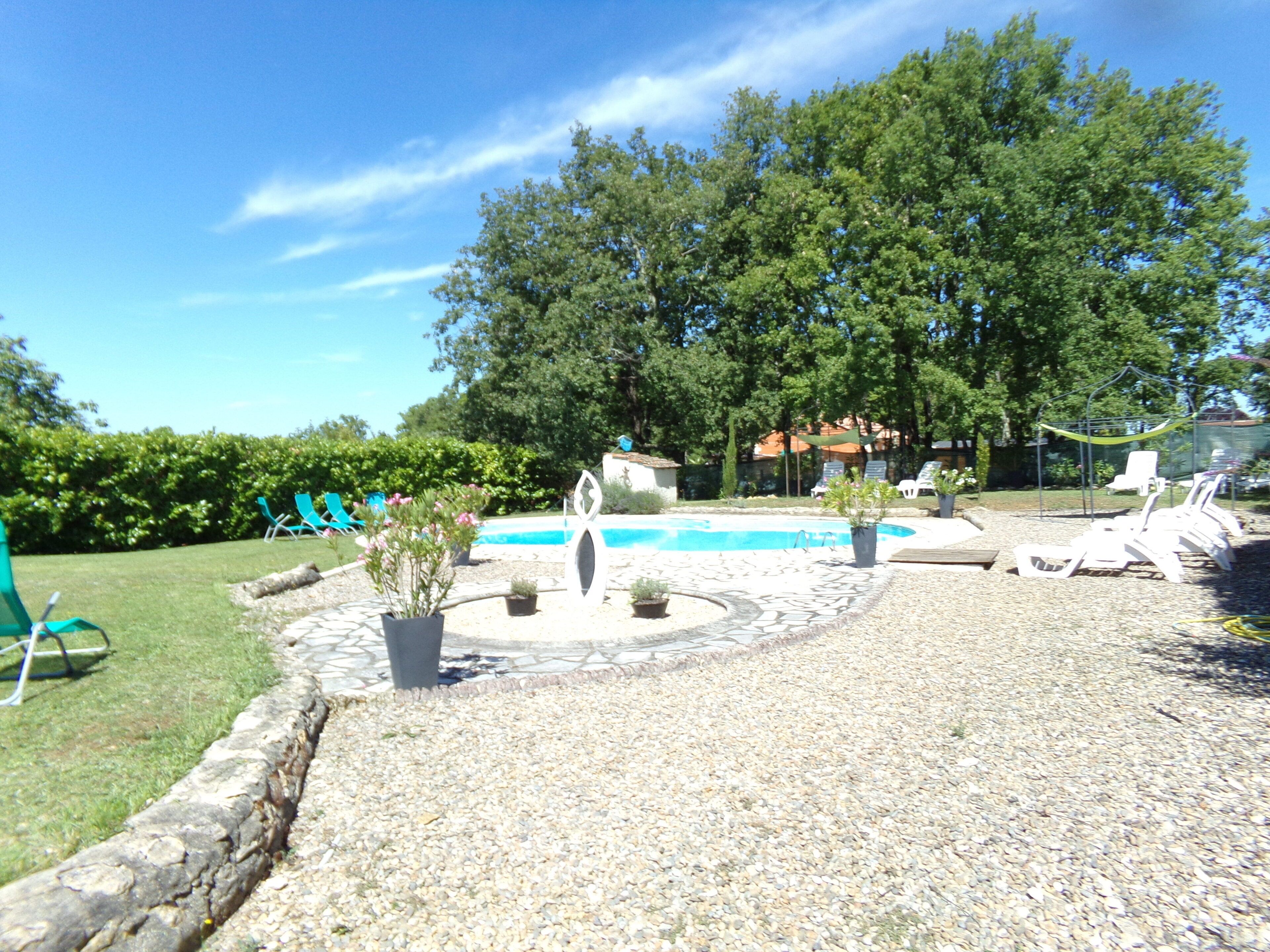 A pool area with lounge chairs, a small garden with potted plants, and a stone pathway leading to the pool.