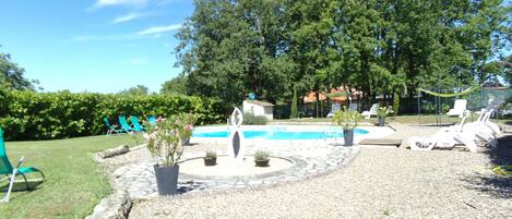 A pool area with lounge chairs, a small garden with potted plants, and a stone pathway leading to the pool.