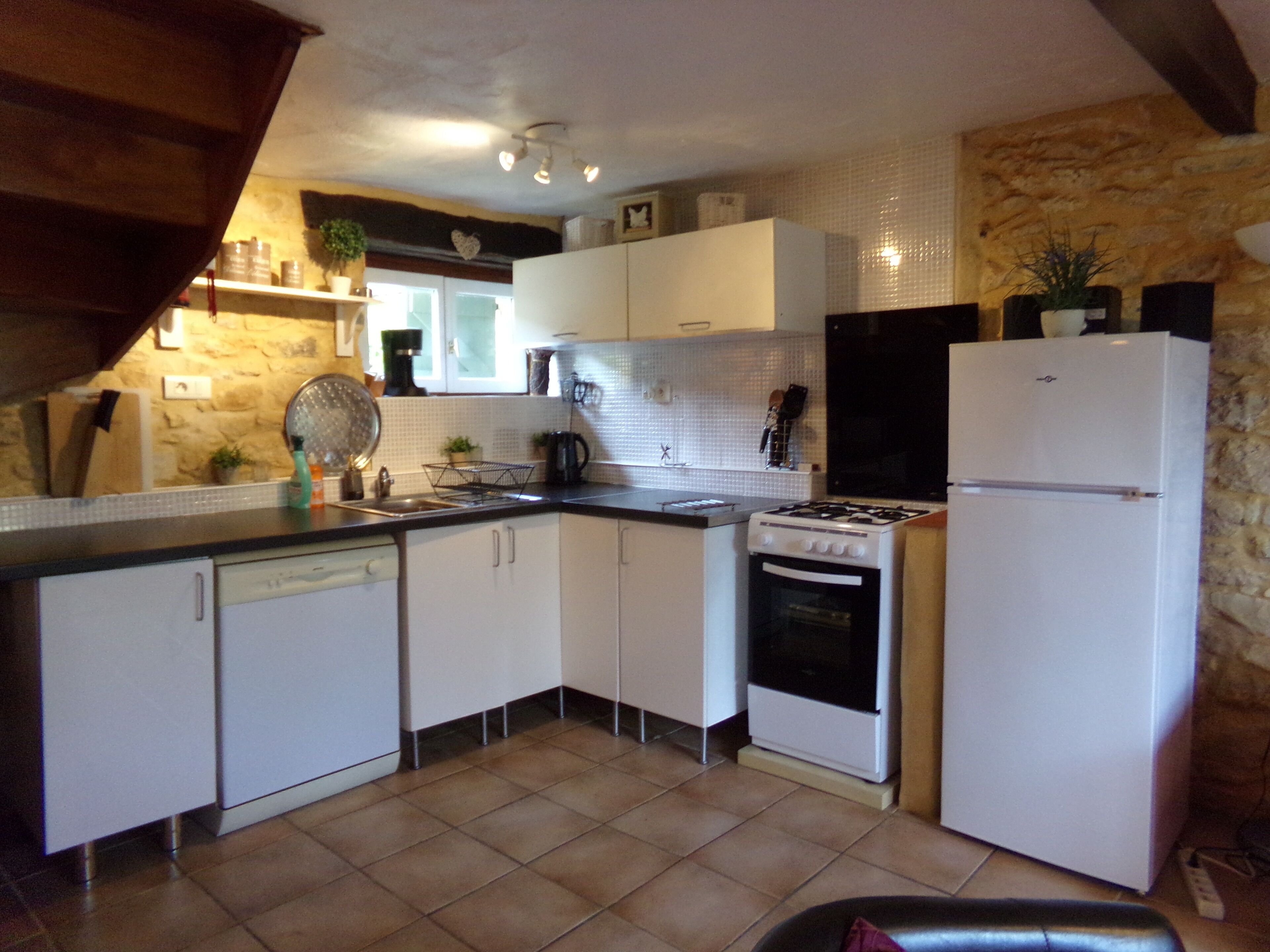 A compact kitchen with white cabinets, a stove, and a refrigerator.