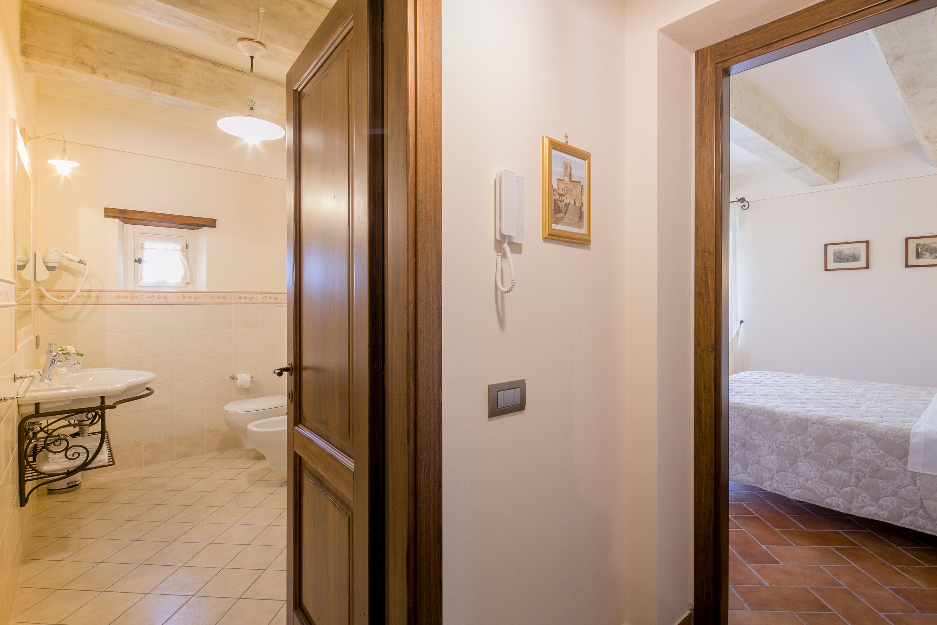 A bathroom with a sink, toilet, and a mirror. There is a door leading to another room.