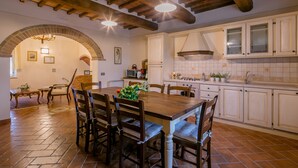 Una cocina amplia con una mesa de comedor de madera, sillas y un arco de ladrillo que conduce a una sala de estar.