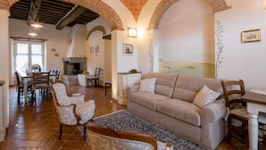 Un amplio salón con un sofá color beige, sillones estampados y una mesa de comedor.