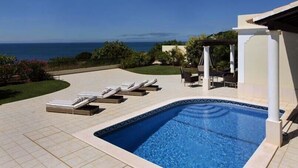 Una piscina con sillas de descanso y vistas al océano.