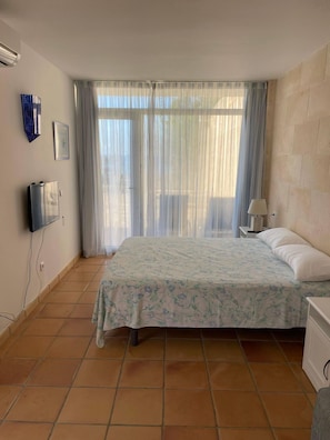 A bedroom with a bed, a nightstand, a lamp, and a TV mounted on the wall.