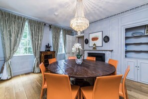 Enjoy meals in this classic dining area with a round table, fireplace, and chandelier.