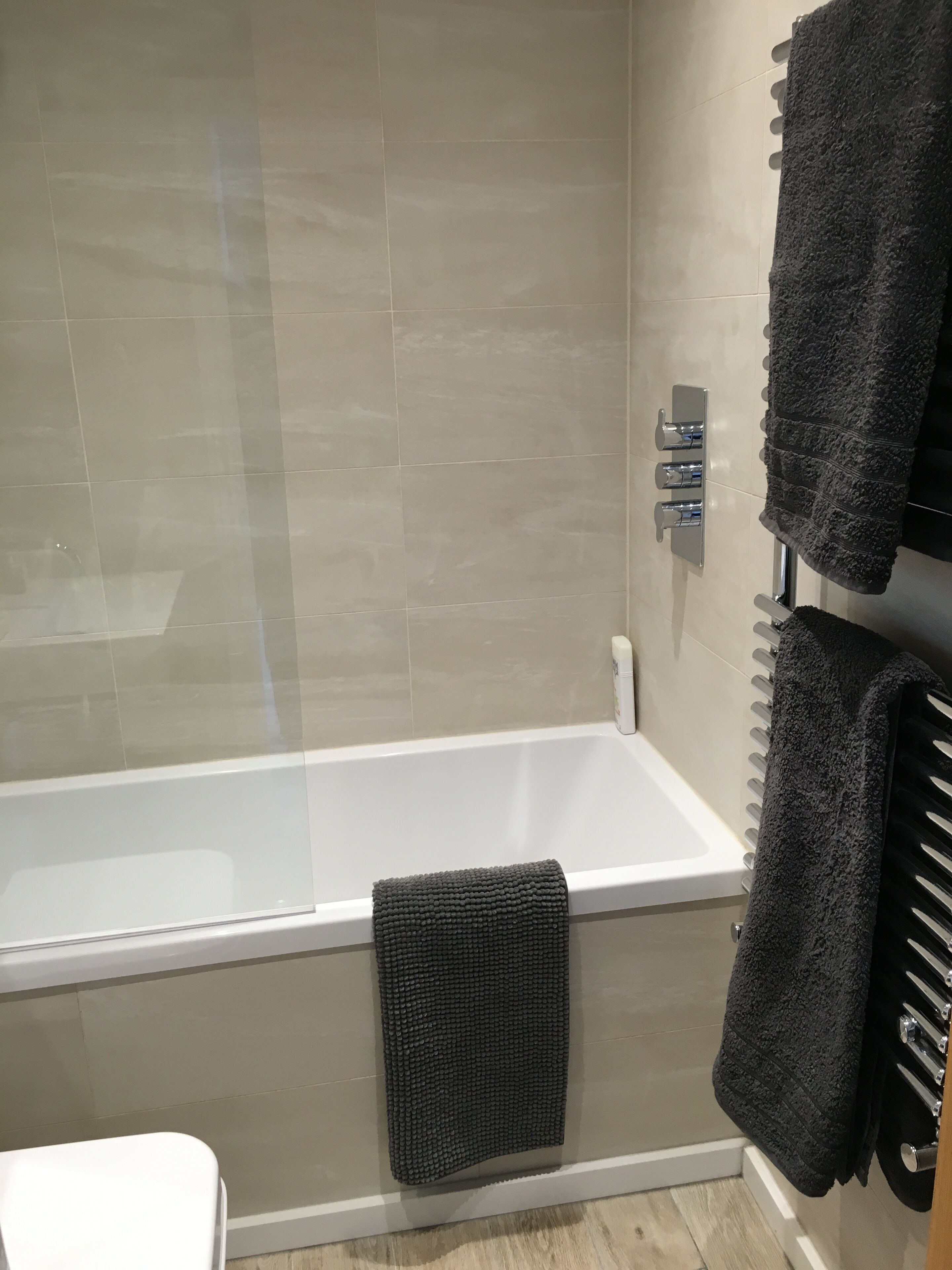 Ein Badezimmer mit einer Badewanne, einer Toilette und einem Handtuchhalter mit zwei Handtüchern.