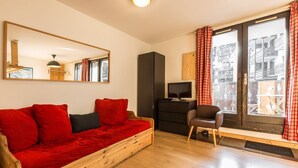 A cozy room with a wooden sofa, a television, and a chair. - Marcel -  an apartment that sleeps 4 guests  in 1 bedroom (Chamonix)