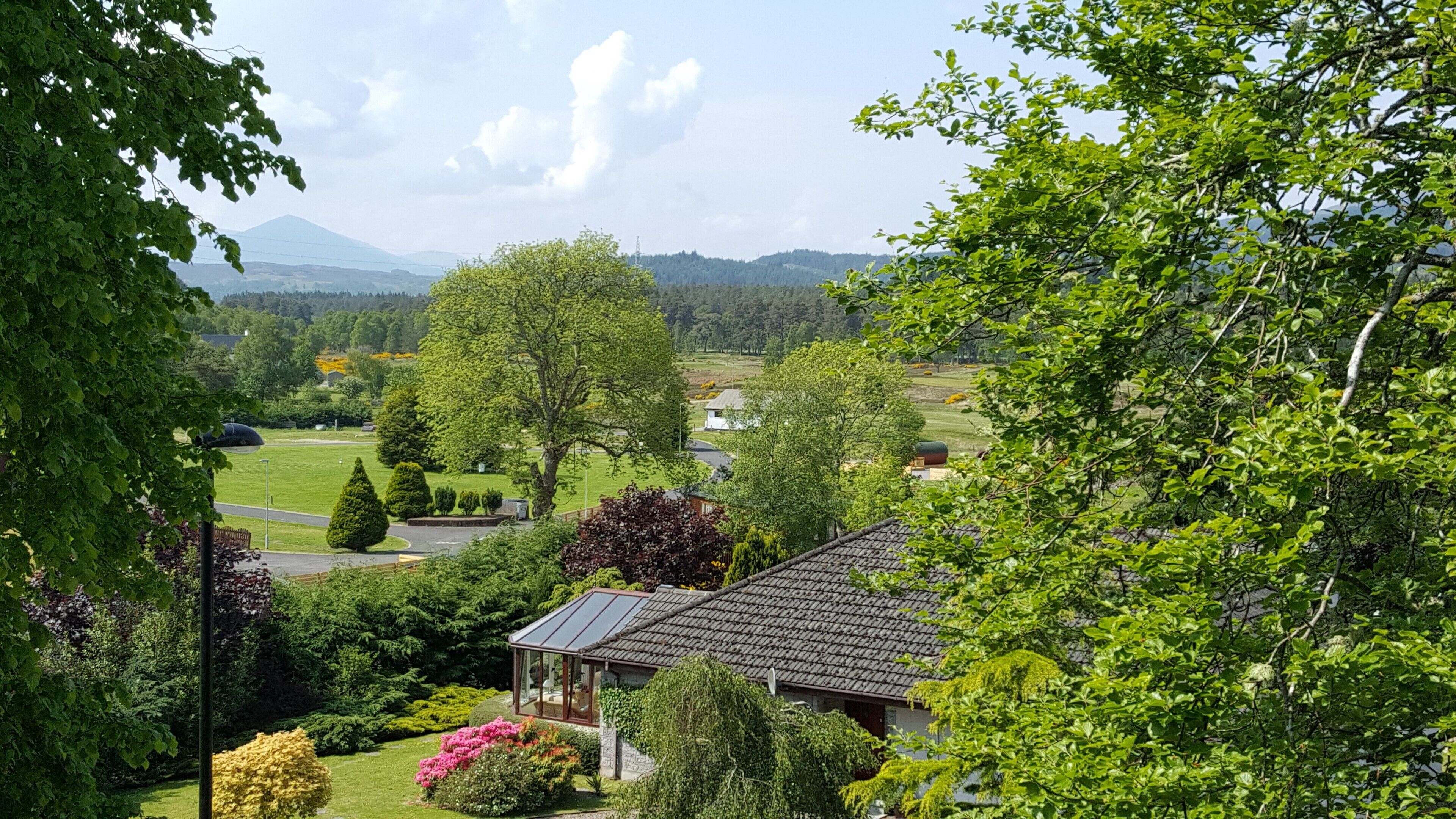 A house with a garden, a view of the countryside, and a mountain in the background.