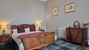 A bedroom with a wooden bed, two bedside tables, a dresser, a radiator, and two framed pictures on the wall. - No.2 The Old Convent (Fort Augustus)