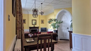 A dining room with a wooden table, chairs, a fireplace, and a television. - No.2 The Old Convent (Fort Augustus)
