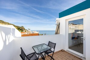 A balcony with a glass door, a small table, and two chairs.