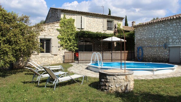 Una casa de piedra con piscina, mobiliario de exterior y un patio cubierto.