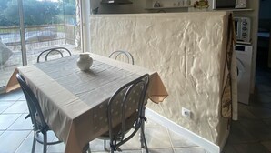 Comedor con mesa y sillas, cocina equipada y vistas a través de amplios ventanales.