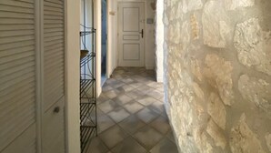 Un pasillo con pared de piedra, una puerta y una barandilla de metal.