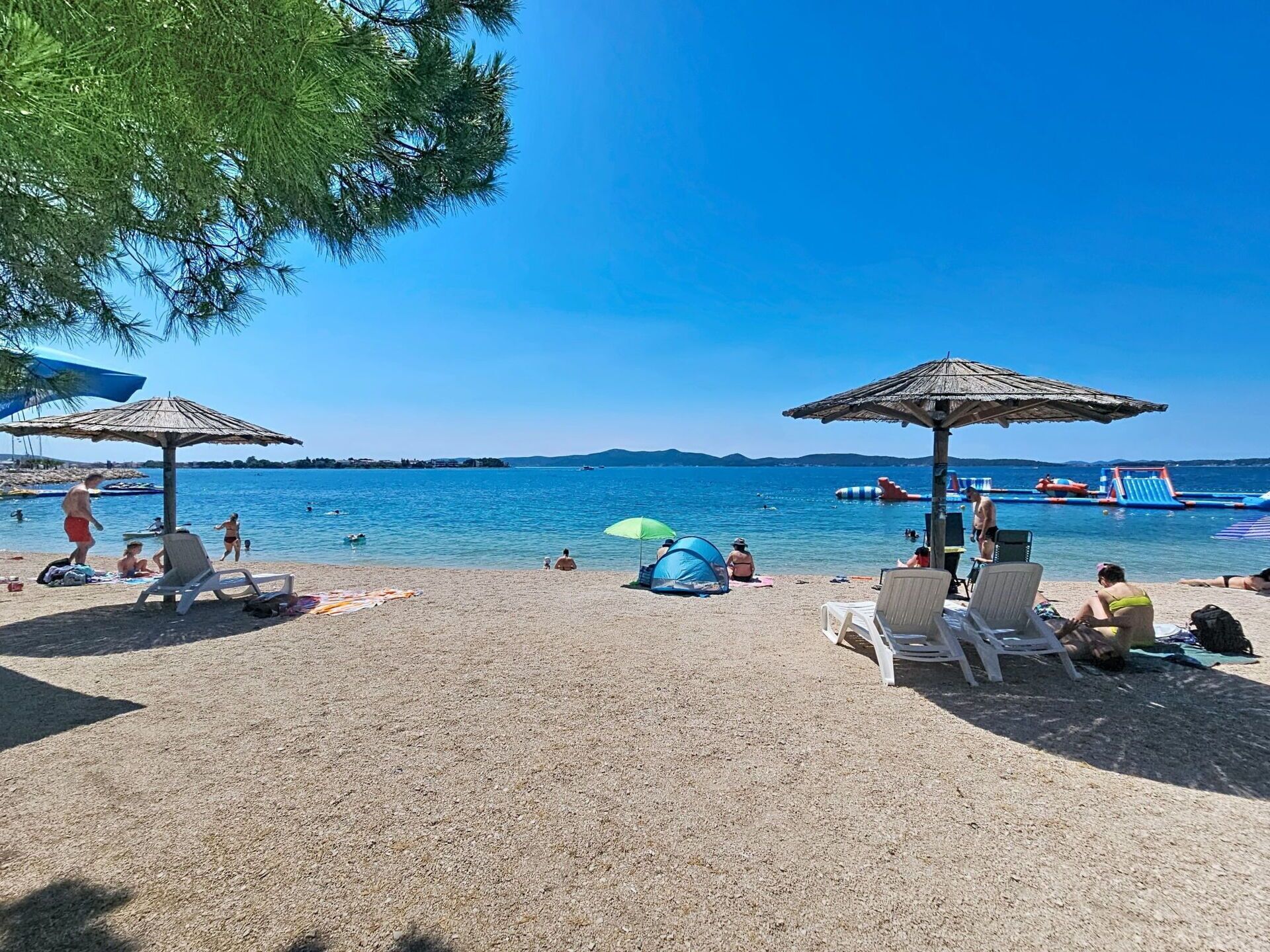 A beach with umbrellas, lounge chairs, and a tent.