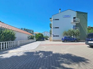 Un immeuble avec une enseigne indiquant « APARTMANI JURČIĆ » et un chemin piétonnier pavé menant à l’entrée.
