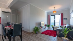 Ein modernes Wohnzimmer mit Essbereich, einem Flachbildfernseher und einem roten Teppich.