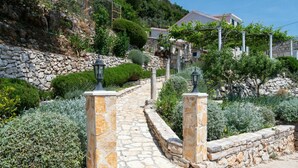 A stone pathway leading to a hillside property with a stone wall and a lamp post.