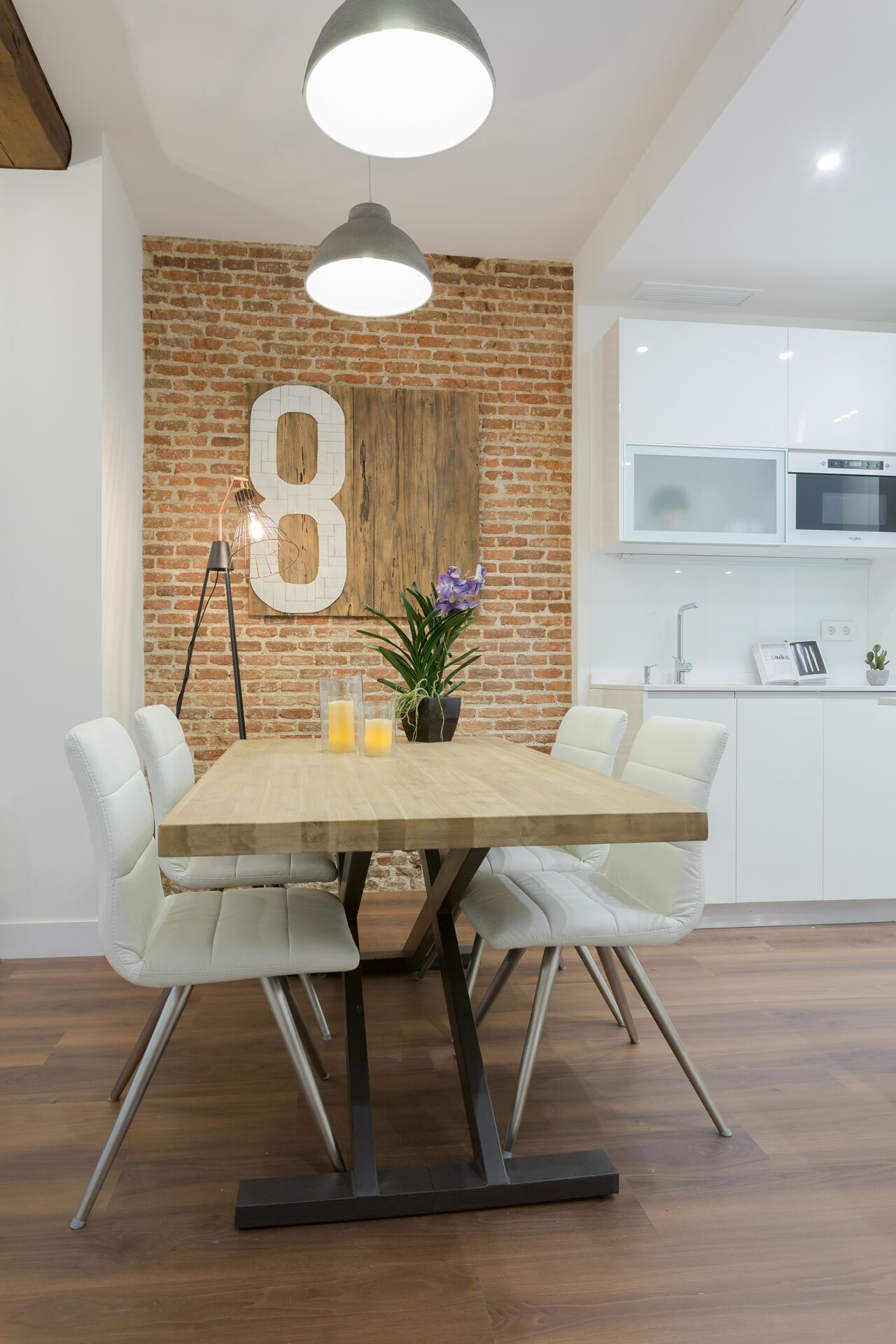 A dining area with a wooden table, white chairs, and a brick wall with a large number '8'.