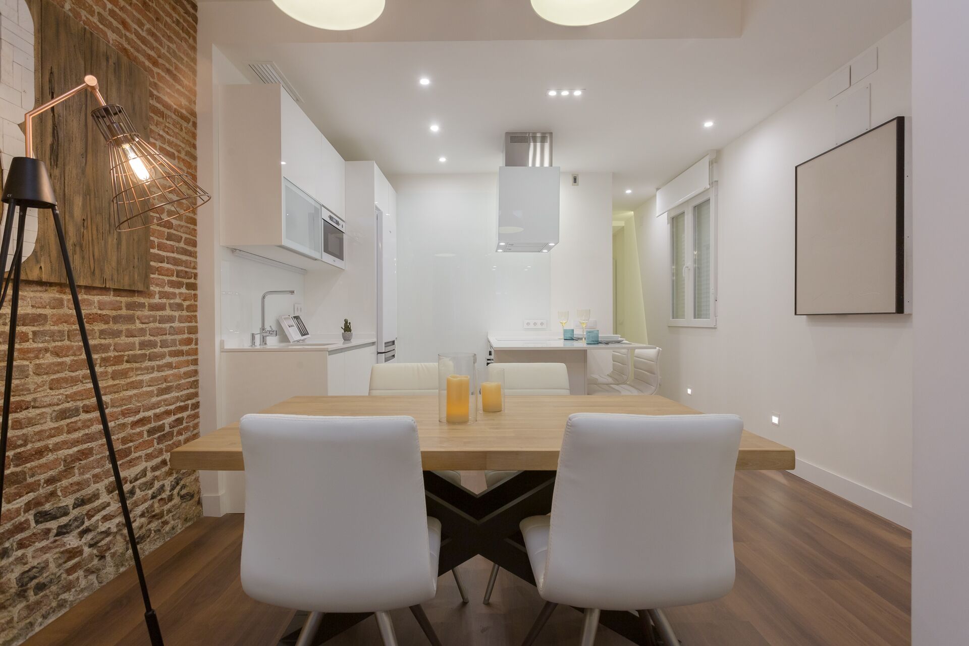 A modern kitchen with white cabinets, a wooden countertop, and a hanging light fixture.