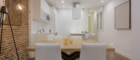A modern kitchen with white cabinets, a wooden countertop, and a hanging light fixture.