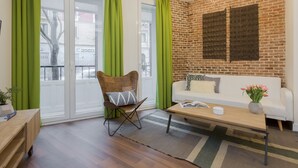 A modern living room with a brick wall, a white sofa, a wooden coffee table, and a green chair.