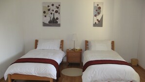 Ein Doppelzimmer mit zwei Betten, einem Nachttisch und einer Wandlampe.