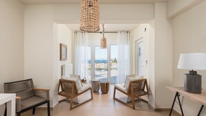 Amplia sala de estar con dos sillones de mimbre, una mesa de madera y una lámpara colgante.