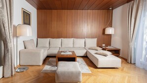 A modern living room with a wooden ceiling, a sectional sofa, a coffee table, and a side table. - Vila Marija - perfect vacation apartment (Ljubljana)