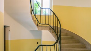 A spiral staircase with a black metal railing, beige carpeted steps, and a white door at the top. - Vila Marija - perfect vacation apartment (Ljubljana)