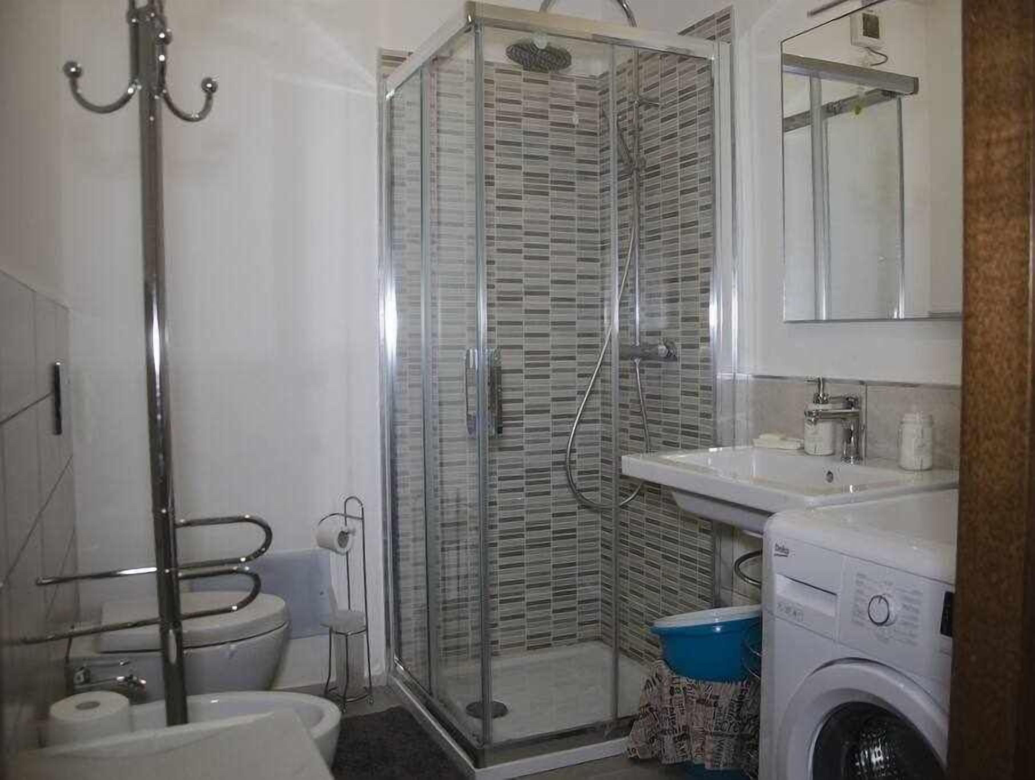 Ein Badezimmer mit Duschkabine, Toilette, Waschbecken und Waschmaschine.