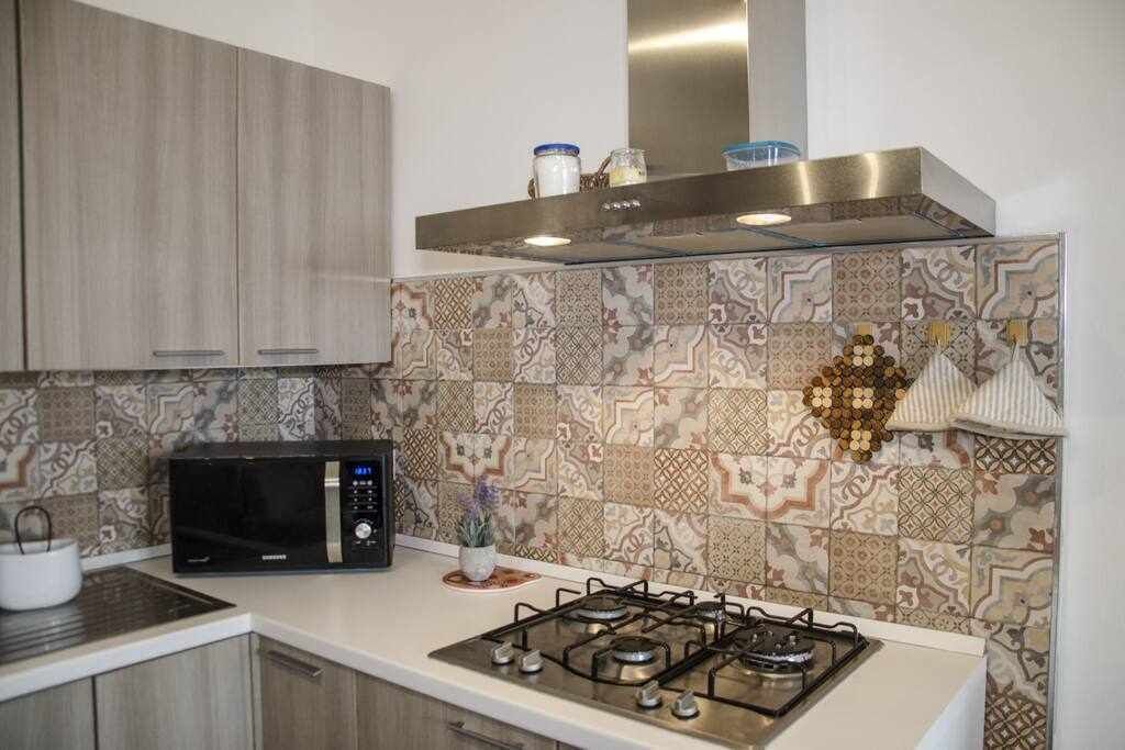 A modern kitchen with a microwave, gas stove, and patterned backsplash.