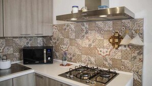 Eine moderne Küche mit Mikrowelle, Gasherd und einer gefliesten Rückwand.