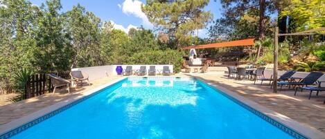 Une piscine avec des chaises longues, un espace barbecue et une terrasse en bois.