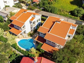 Experience Mediterranean-inspired living with a pool surrounded by lush greenery and a stone pathway.