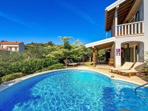Relax by the pool surrounded by lush greenery and enjoy a barbecue on the adjacent deck.