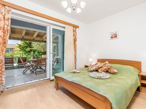 Relax in this serene bedroom with a comfortable bed, outdoor patio access, and a peaceful view.