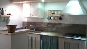 A kitchen with a central island, cabinets, a microwave, and a TV mounted on the wall. - The Casetta di Merau Sant'Antioco (Sant'Antioco)