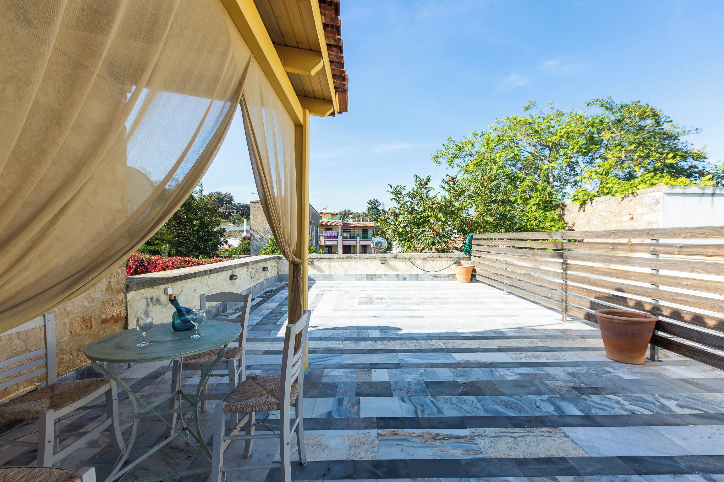 Una terraza con mesa y sillas, una planta en maceta y vistas del entorno.