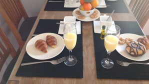 Un desayuno con cruasanes, zumo de naranja y bollería sobre una mesa.
