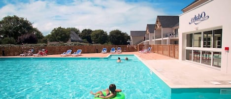 Una piscina con sillas de descanso y un edificio con un letrero.