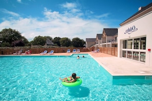 A swimming pool with lounge chairs and a building with a sign.