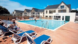 Uma área de piscina com espreguiçadeiras e um edifício com uma placa que diz 'OBIS'.