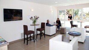 Uma área de espera moderna com assentos, televisão e vista pela janela.